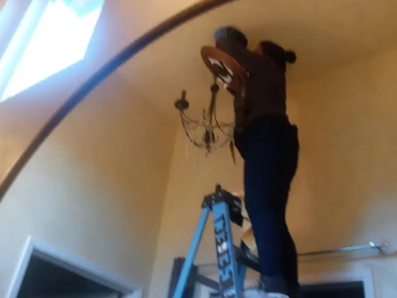 Electrician installing a chandelier in a Ballville residence